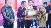 Sekda Prov. Sultra Asrun Lio (Kanan) saat menyerahkan piagam kepada Kadis Kominfo Bombana, Sofian Baco (Kiri)