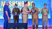 Gubernur Sulawesi Tenggara, Mayjen TNI (Purn) Andi Sumangerukka, S.E., M.M menyerahkan penghargaan kepada Bupati Bombana, Ir. H. Burhanuddin, M.Si